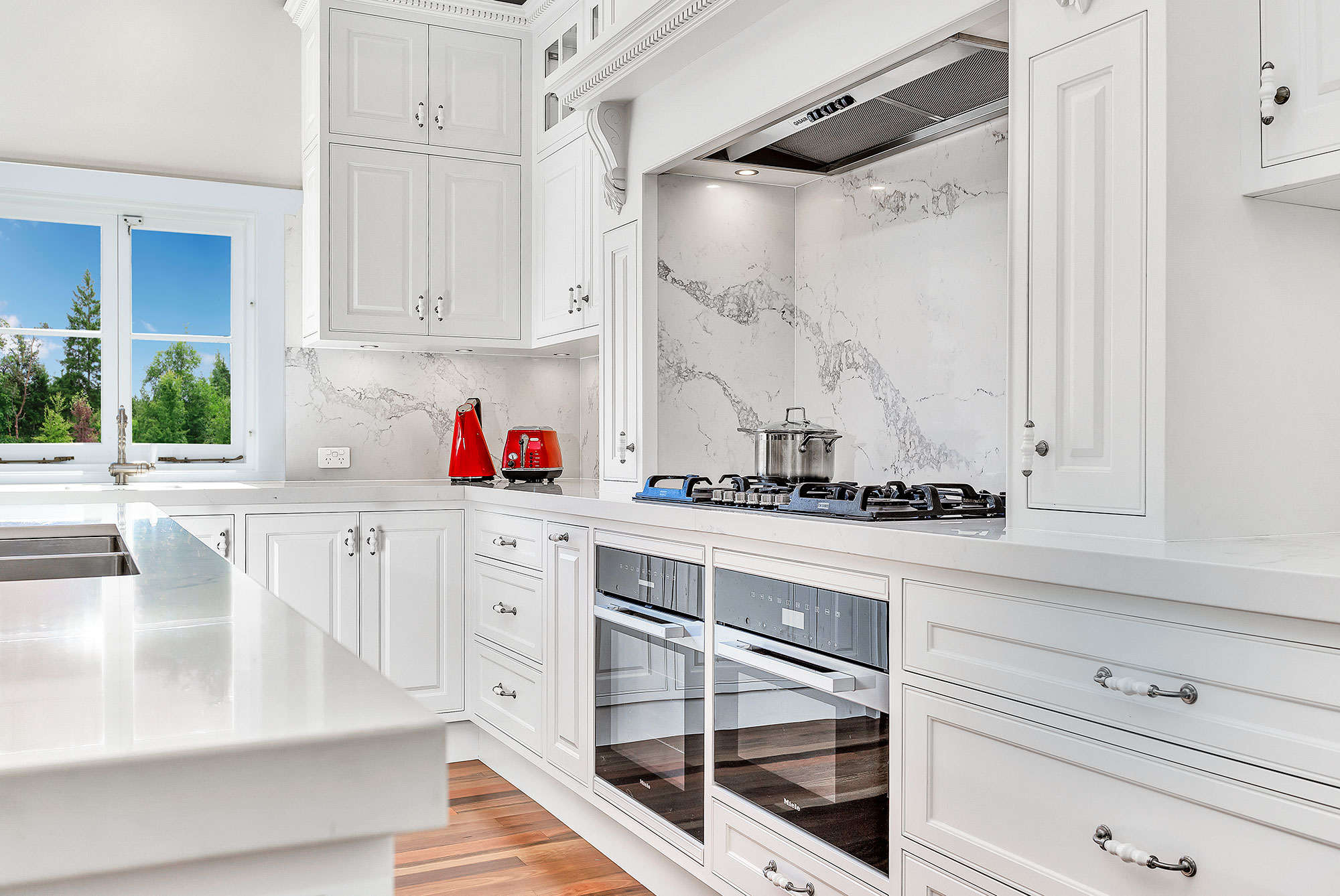 A spacious and bright kitchen with white cabinets, subway tile backsplash, and an island with a wooden countertop